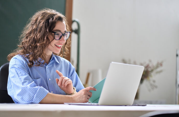 Young business woman leading hybrid online remote video call working in office.